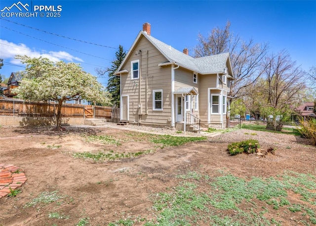 rear view of house with a chimney, a fenced backyard, and entry steps