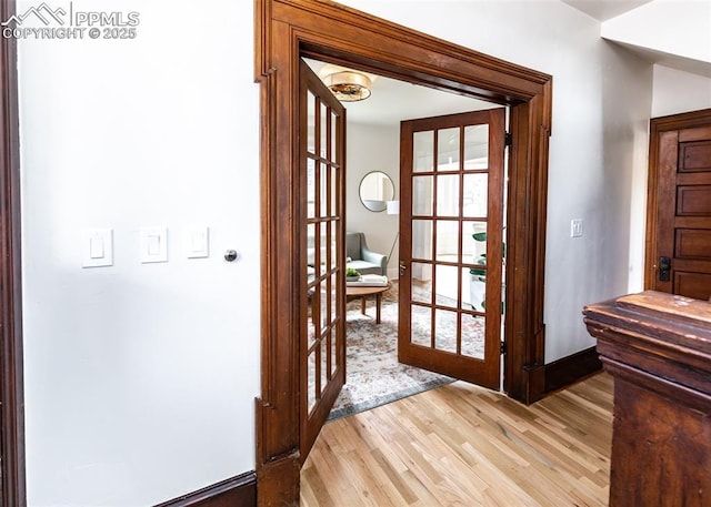entryway featuring baseboards, light wood finished floors, and french doors