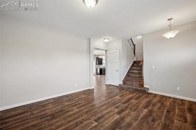7318 Dutch Loop, Colorado Springs, CO 80925 - unfurnished living room with baseboards, stairs, and dark wood-type flooring