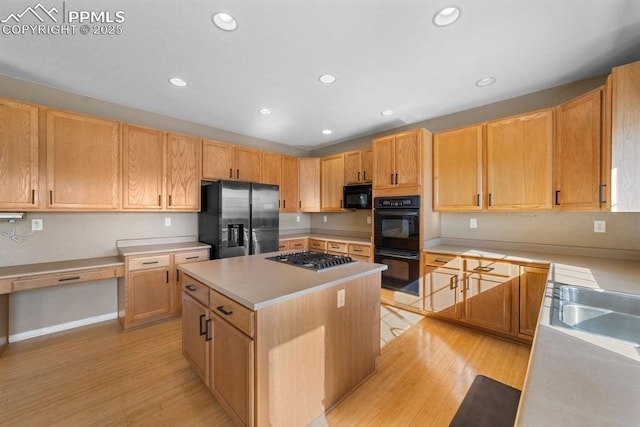 9089 Royal Melbourne Cir, Peyton, CO 80831 - kitchen with light wood-style floors, a center island, black appliances, and light countertops