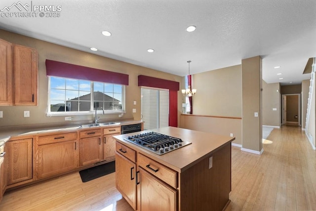 9089 Royal Melbourne Cir, Peyton, CO 80831 - kitchen featuring an inviting chandelier, stainless steel gas cooktop, a kitchen island, light wood-style floors, and a sink