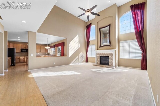 9089 Royal Melbourne Cir, Peyton, CO 80831 - unfurnished living room featuring ceiling fan, light wood-type flooring, baseboards, and a towering ceiling