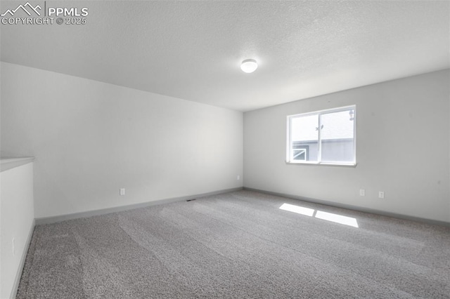 carpeted spare room featuring baseboards and a textured ceiling