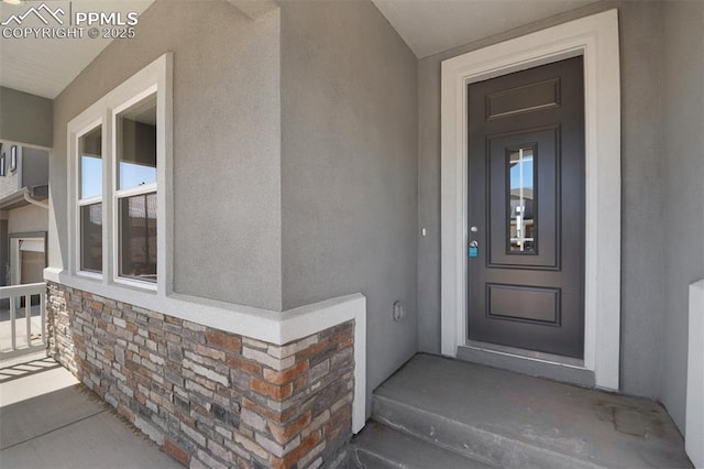 property entrance featuring stone siding and stucco siding
