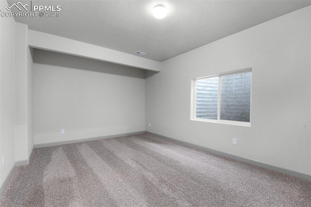 carpeted empty room featuring a textured ceiling, visible vents, and baseboards