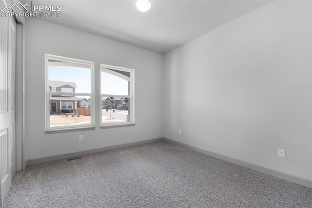carpeted empty room featuring baseboards and visible vents