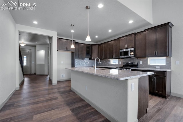 kitchen featuring dark wood-style flooring, range, tasteful backsplash, a sink, and stainless steel microwave