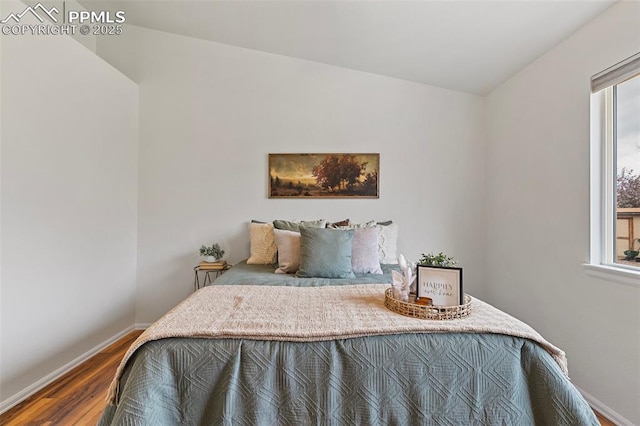 bedroom with baseboards, wood finished floors, and multiple windows