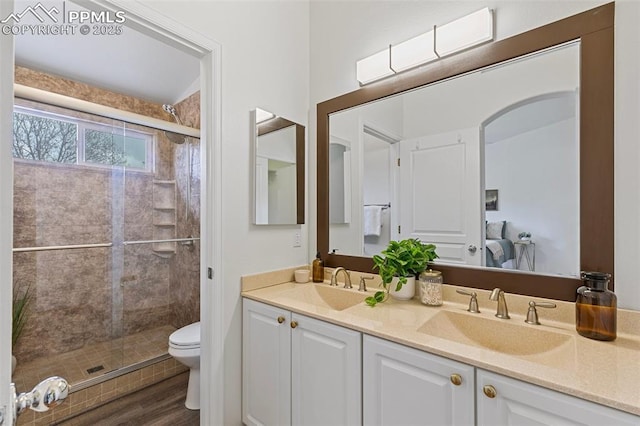 bathroom with toilet, a stall shower, double vanity, and wood finished floors