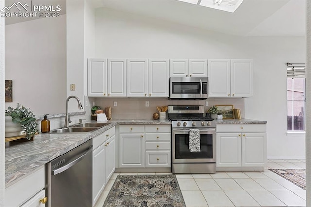 kitchen with stainless steel appliances, a sink, light tile patterned floors, white cabinets, and high vaulted ceiling