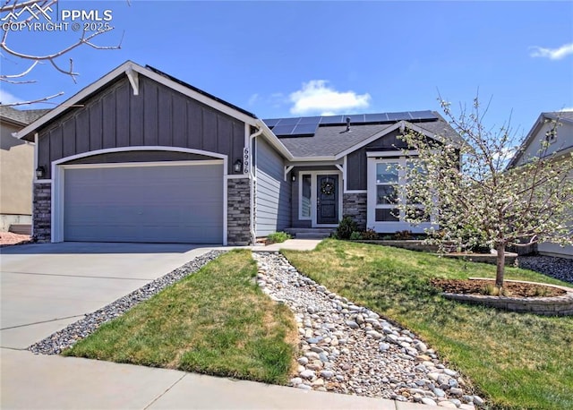 6996 Mustang Rim Dr, Colorado Springs, CO 80923 - ranch-style house with stone siding, board and batten siding, roof mounted solar panels, an attached garage, and driveway