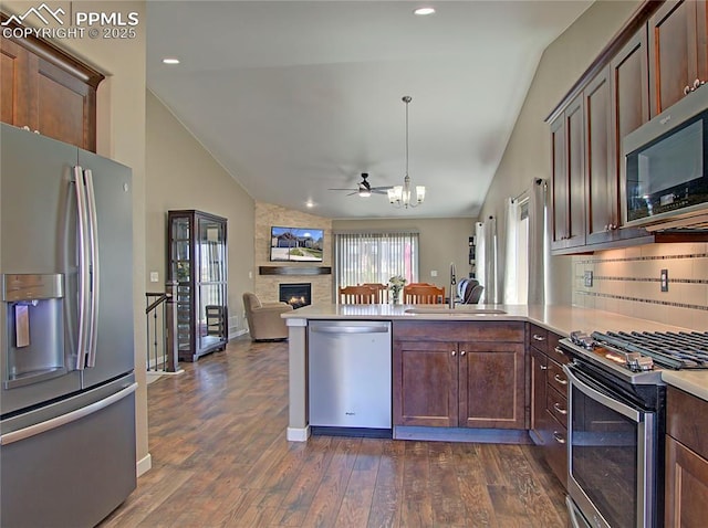 6996 Mustang Rim Dr, Colorado Springs, CO 80923 - kitchen featuring appliances with stainless steel finishes, a sink, a peninsula, open floor plan, and lofted ceiling