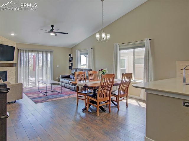 6996 Mustang Rim Dr, Colorado Springs, CO 80923 - dining space with ceiling fan with notable chandelier, a fireplace, vaulted ceiling, and dark wood-style floors