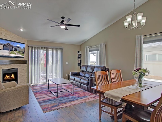 6996 Mustang Rim Dr, Colorado Springs, CO 80923 - dining space featuring ceiling fan with notable chandelier, vaulted ceiling, dark wood-style floors, and a stone fireplace