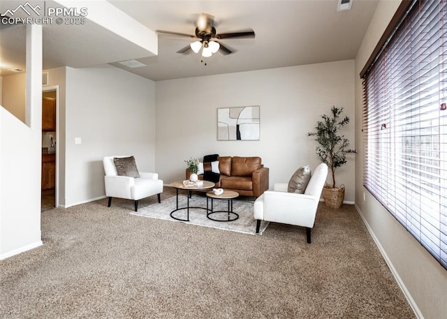 carpeted living area featuring a ceiling fan and baseboards