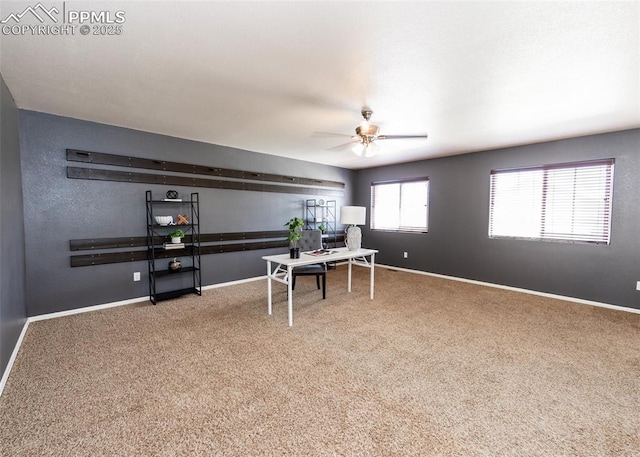 carpeted office space featuring baseboards and ceiling fan