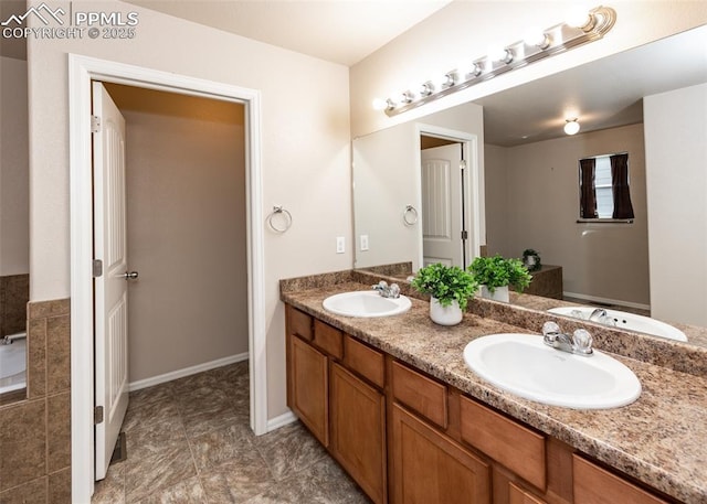 full bath featuring a sink, baseboards, and double vanity