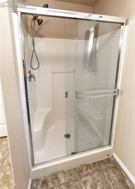 bathroom with baseboards and a shower stall