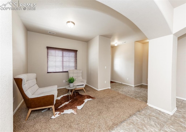 sitting room with visible vents, arched walkways, and baseboards
