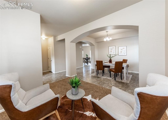 living room with baseboards, arched walkways, and an inviting chandelier