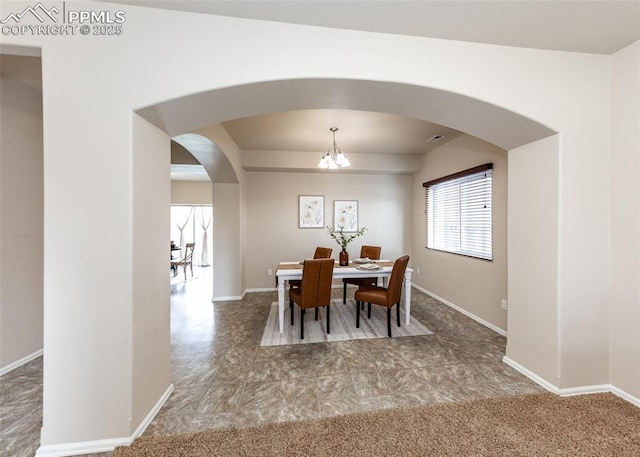 dining space with carpet floors, arched walkways, baseboards, and a notable chandelier