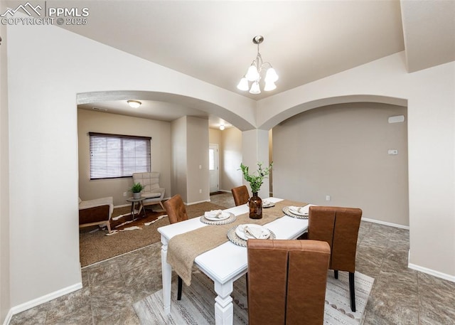 dining area with arched walkways, baseboards, an inviting chandelier, and lofted ceiling