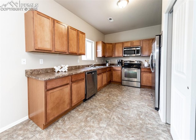 kitchen featuring brown cabinetry, visible vents, appliances with stainless steel finishes, a sink, and baseboards