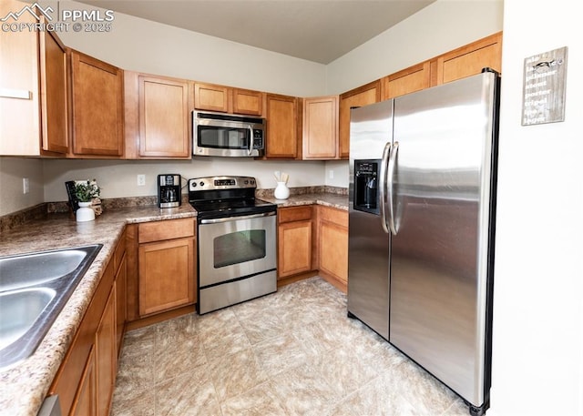 kitchen featuring a sink, appliances with stainless steel finishes, brown cabinetry, and dark countertops