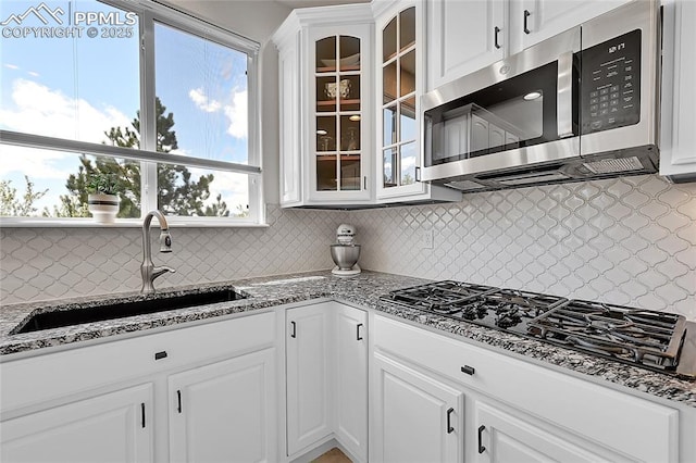 kitchen with a sink, decorative backsplash, stainless steel microwave, and black gas cooktop
