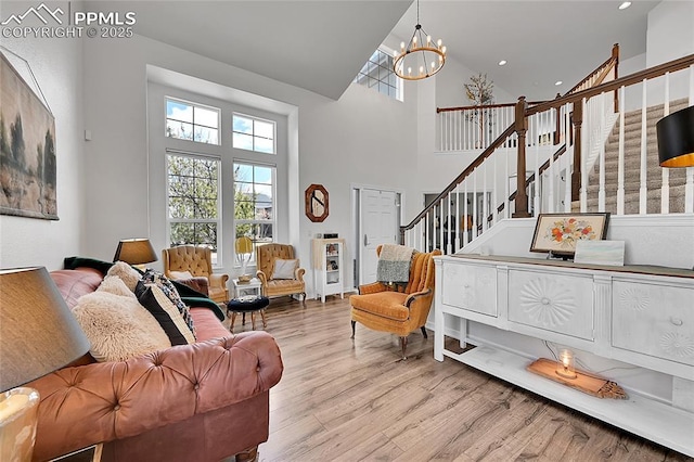 living area featuring stairs, a notable chandelier, a healthy amount of sunlight, and wood finished floors