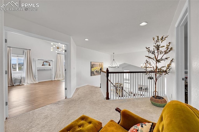 hallway featuring carpet floors, recessed lighting, an inviting chandelier, and an upstairs landing