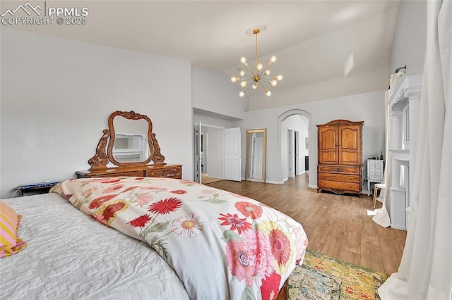 bedroom with arched walkways, wood finished floors, a notable chandelier, and high vaulted ceiling