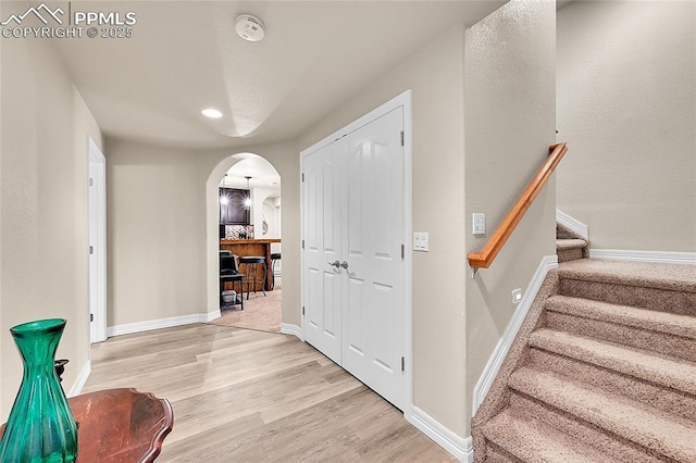 interior space with stairway, arched walkways, baseboards, and light wood-type flooring