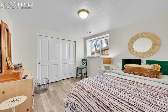 bedroom with baseboards, a closet, light wood finished floors, and visible vents
