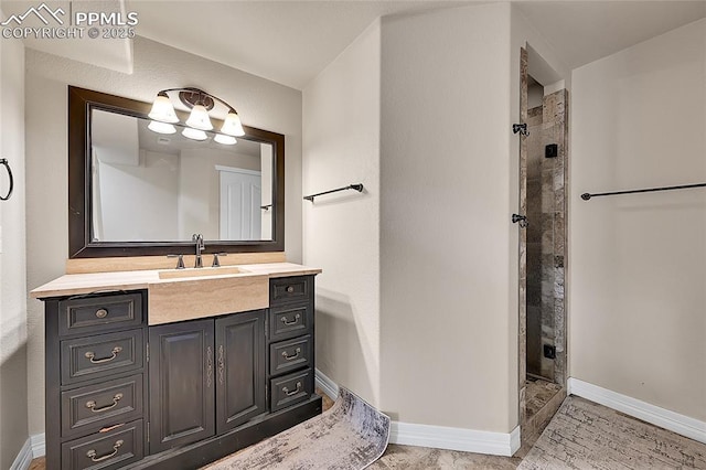 bathroom with vanity, baseboards, and a tile shower