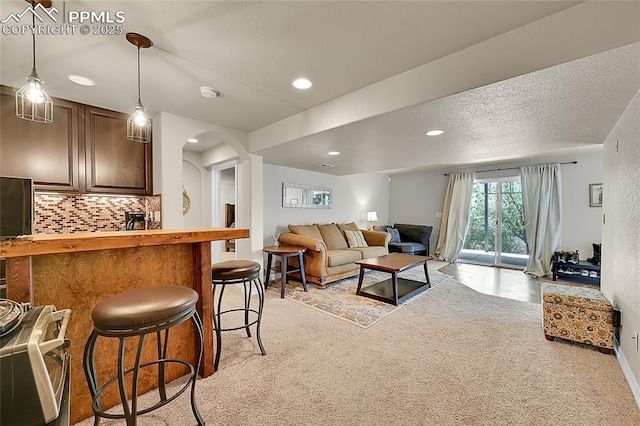 living room with arched walkways, light carpet, and recessed lighting
