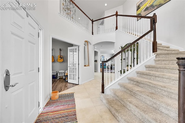 entrance foyer with tile patterned flooring, arched walkways, recessed lighting, baseboards, and stairway