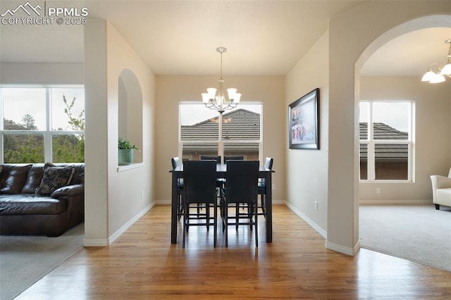 2532 Sierra Oak Dr, Colorado Springs, CO 80919 - dining room featuring an inviting chandelier, arched walkways, baseboards, and light wood finished floors