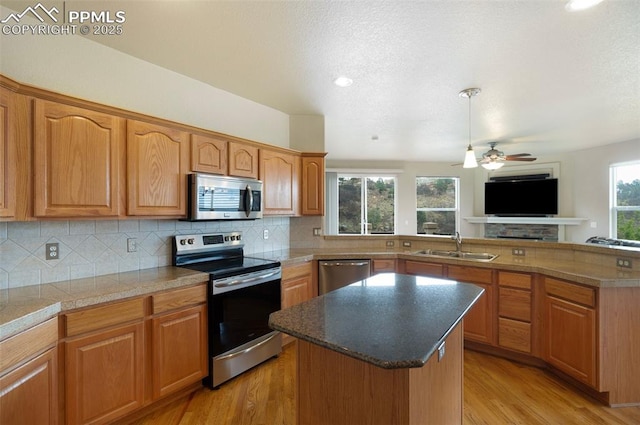 2532 Sierra Oak Dr, Colorado Springs, CO 80919 - kitchen featuring light wood-style floors, ceiling fan, a center island, appliances with stainless steel finishes, and backsplash