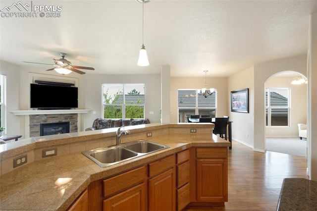 2532 Sierra Oak Dr, Colorado Springs, CO 80919 - kitchen with wood finished floors, a sink, open floor plan, a glass covered fireplace, and tile counters