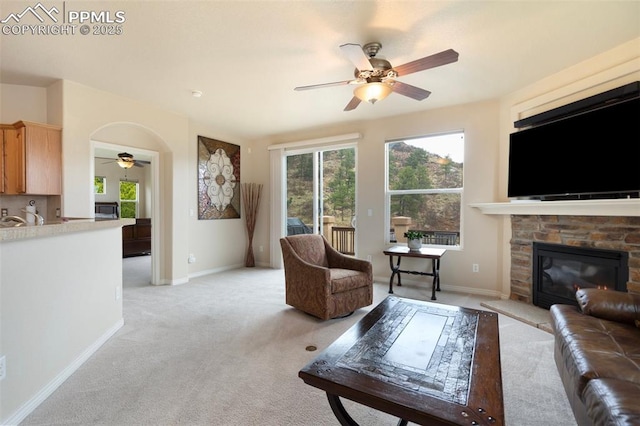2532 Sierra Oak Dr, Colorado Springs, CO 80919 - living area with light colored carpet, a ceiling fan, a stone fireplace, and a wealth of natural light