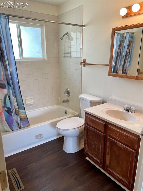 136 Sumac Dr, Colorado Springs, CO 80911 - bathroom featuring visible vents, wood finished floors, vanity, toilet, and shower / bathtub combination with curtain