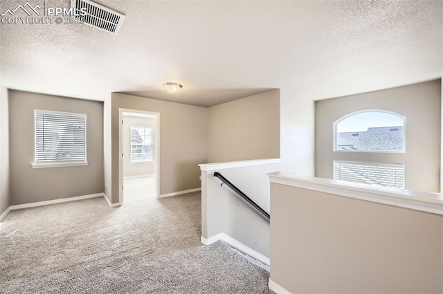 8094 Misty Moon Dr, Colorado Springs, CO 80924 - hall featuring visible vents, baseboards, a textured ceiling, carpet, and an upstairs landing