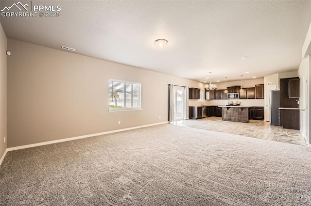 8094 Misty Moon Dr, Colorado Springs, CO 80924 - unfurnished living room featuring light colored carpet, baseboards, a chandelier, and visible vents