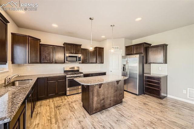 8094 Misty Moon Dr, Colorado Springs, CO 80924 - kitchen with dark brown cabinetry, a kitchen island, a sink, light stone counters, and stainless steel appliances