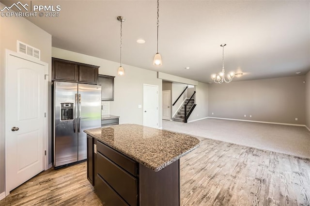 8094 Misty Moon Dr, Colorado Springs, CO 80924 - kitchen featuring dark brown cabinetry, stainless steel fridge, a center island, stone counters, and visible vents