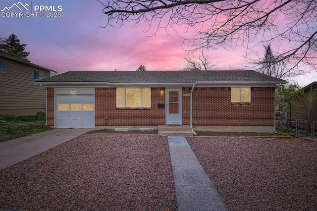 ranch-style home featuring fence, roof with shingles, brick siding, an attached garage, and driveway