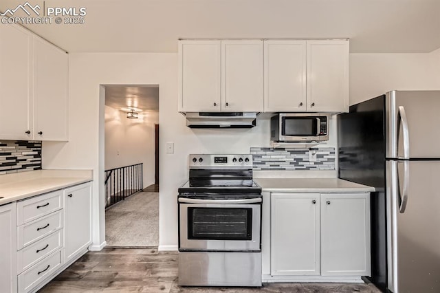 kitchen featuring under cabinet range hood, white cabinetry, appliances with stainless steel finishes, and light countertops