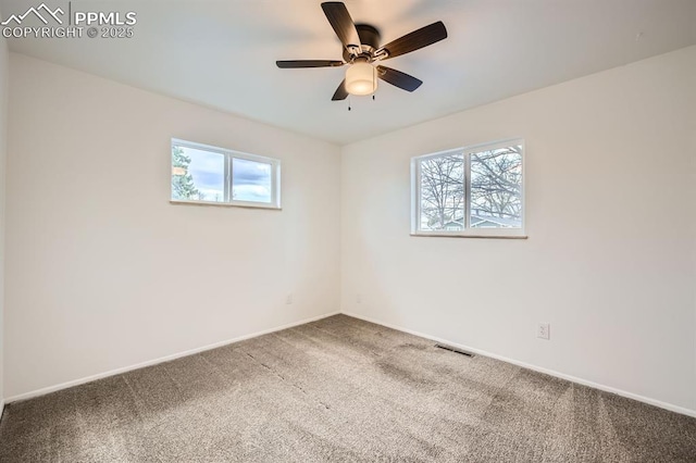 carpeted empty room with a healthy amount of sunlight, baseboards, and visible vents