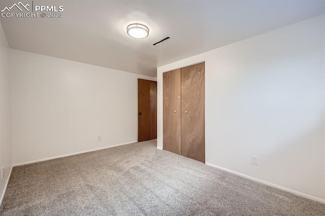 unfurnished bedroom with a closet, carpet, baseboards, and visible vents